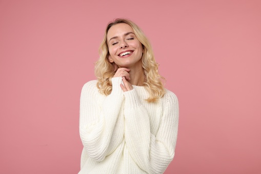 Happy woman in stylish warm sweater on pink background