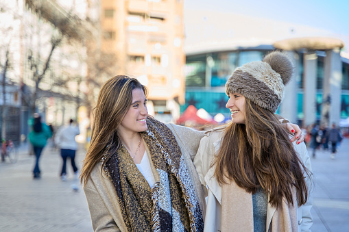 Forging Urban Friendships: Two Young Women Walking Through the City, Locking Eyes and Sharing Smiles