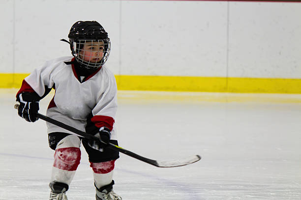 Child playing ice hockey in a white uniform  stock photo