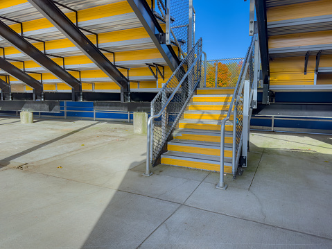 Example of an exit, entrance, vomitorium at empty set of metal stadium bleacher - grandstands with steps and railing. Nondescript location with no people in image. Not a ticketed event.