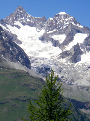 View across a deep glacial valley from near the village of Riffelalp near Zermatt up to peaks and ridges near the Matterhorn that shows many classic mountain glaciation landforms including a Horn, Cirques, arêtes,hanging glaciers, moraines, hanging valleys, and more.