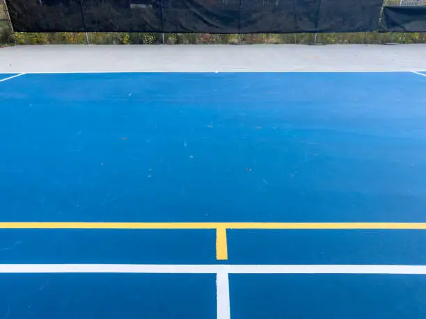 Photo of Close up photo of a outdoor blue tennis court with white lines combined with yellow, gold, pickleball lines.