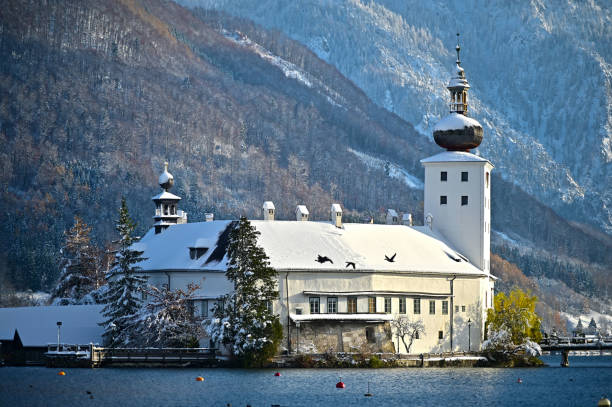 The Seeschloss Ort on Lake Traunsee in Gmunden in winter with snow The romantic world famous Ort lake castle on an island on Lake Traunsee in Gmunden in winter with snow and the mountain Traunstein in the background seeschloss stock pictures, royalty-free photos & images