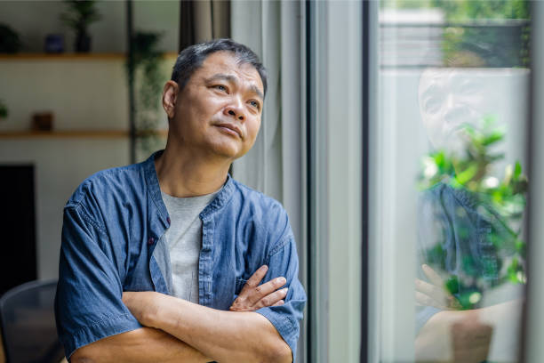 thoughtful man looking through window at home
