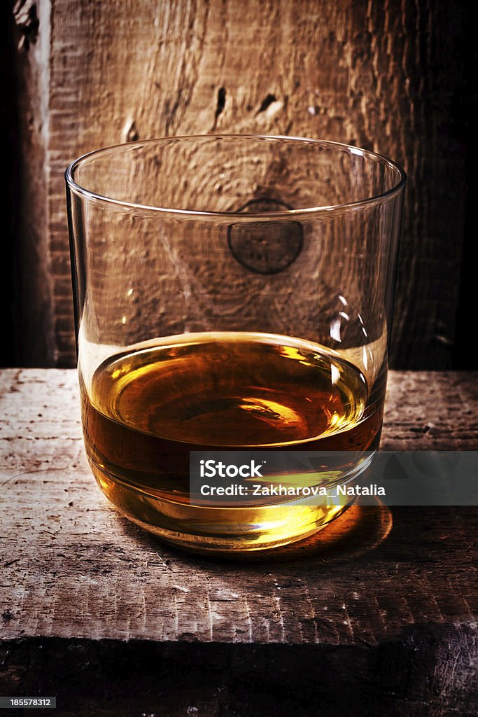 Whiskey Scotch in a glass and  bottle on old wooden Whisky Scotch in a glass and a bottle on old wooden table. Old vintage oak countertop and glass of hard alcohol.Close up. Alcohol - Drink Stock Photo