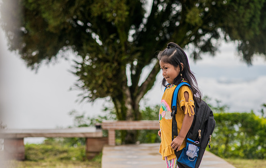 Portrait of little indigenous girl looking sideways in the open air with her backpack on her back.