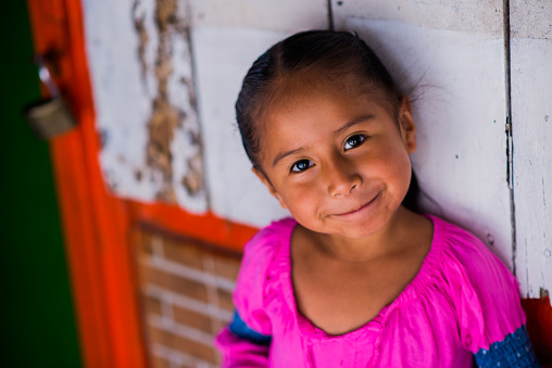 portrait of a little indigenous girl smiling on a coloured and wooden background