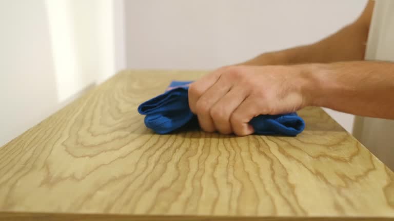 Cropped View Of A Person Folding Shirt Over Wooden Table. Close-up