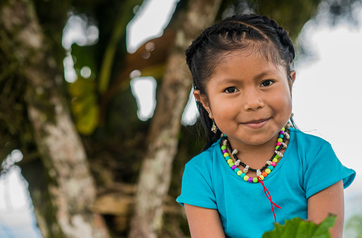 indigenous girl looking at the camera while smiling and nature in the background