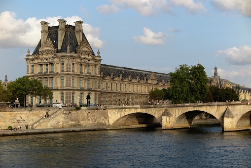 Paris, France - Sept. 29, 2023:  The Musee du Louvre sits on the Right Bank of the Seine River, illuminated by late afternoon sun.