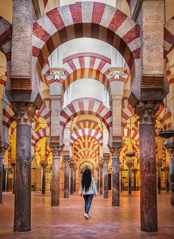 Rear view of a tourist woman visiting the Mezquita (Spanish for mosque) of Cordoba is a Roman Catholic cathedral and former mosque situated in the Andalusian city of Codoba, Spain