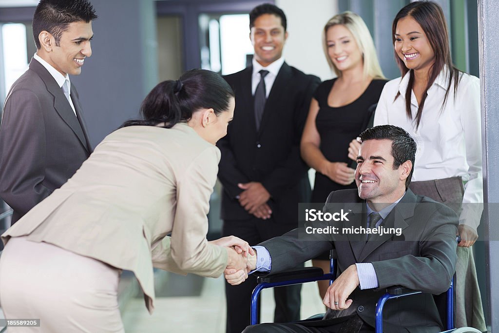 businesswoman greeting handicapped business partner young businesswoman greeting handicapped business partner and team Disability Stock Photo