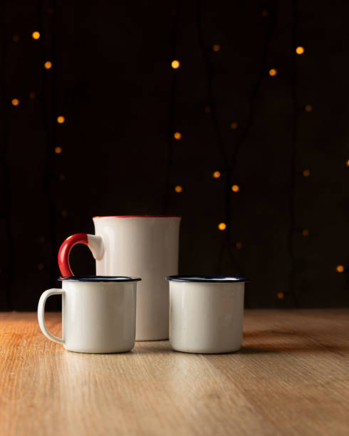 istock Three pewter cups on a light wooden table and Christmas lights in the background 1855924482