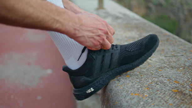 istock Athlete tying sneakers shoelaces outdoors closeup. Hands prepare training shoes. 1855933025
