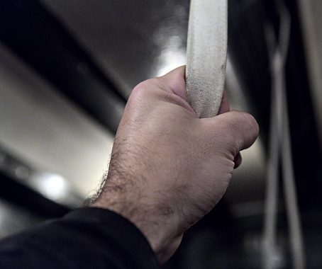 hand holding a strap on a subway car close up (vintage old time historic antique rail) man, straphanger, commute, commuter riding train (history, past, black and white) metro handle