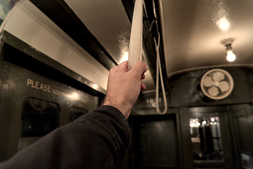 hand holding a strap on a subway car close up (vintage old time historic antique rail) man, straphanger, commute, commuter riding train (history, past, black and white) metro handle