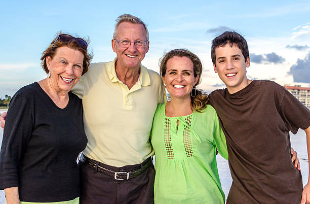 Three generations Grandparents, daughter and grandchild posing happily on a family day on the beach grandmother real people front view head and shoulders stock pictures, royalty-free photos & images