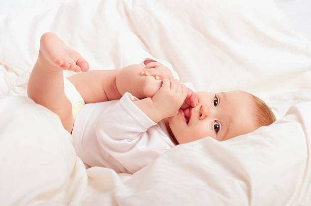 istock small baby sucking her finger on leg 185601377