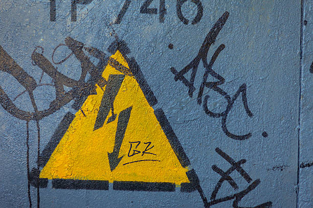 Panneau d'avertissement jaune haute tension recouverte de graffitis - Photo