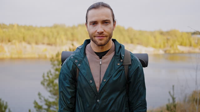 Man hiker standing and looking at camera in autumn area
