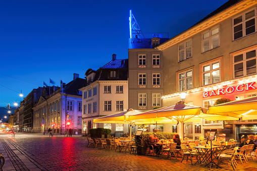 People sit at pub-restaurant patios in downtown Copenhagen, Denmark in the evening.