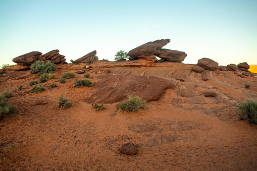 Scenic Boulders atop a mound in the Arizona Desert. The Red desert sand and low green shrubs lead up a mound with boulders atop a mound. Taken in the early morning, the light makes it look like an alien landscape. A nice rugged landscape in a remote arid setting. Plenty of copy space.