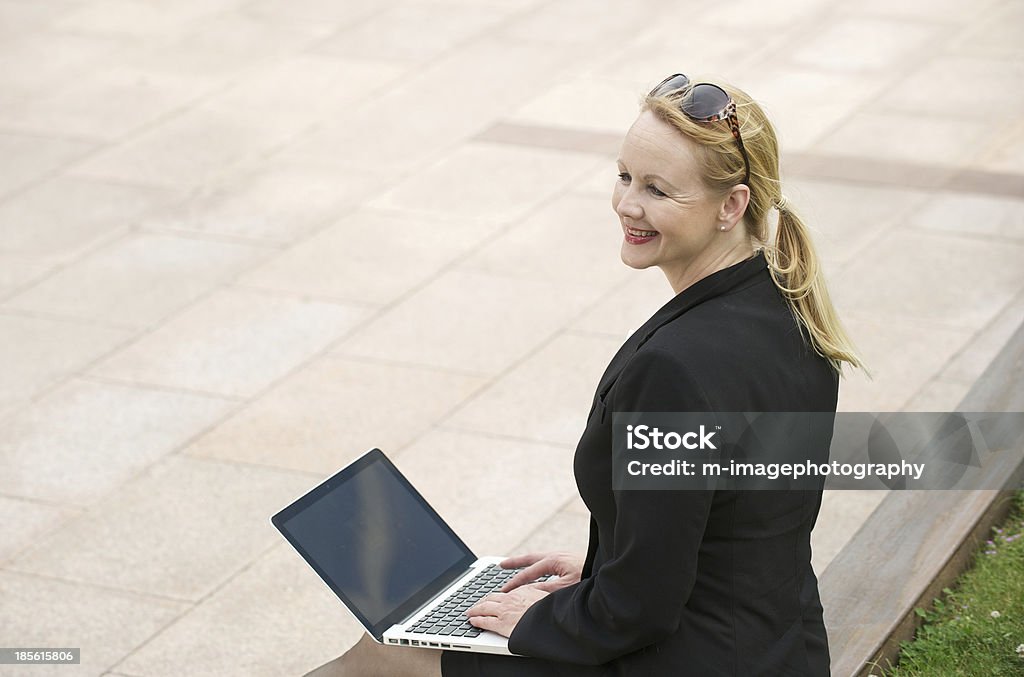 Empresaria sonriendo al aire libre con capacidad para una computadora portátil - Foto de stock de Adulto libre de derechos