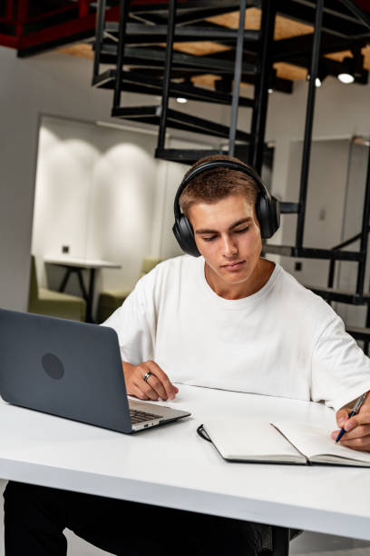 istock Young man wearing headphones while studying with laptop 1856172894