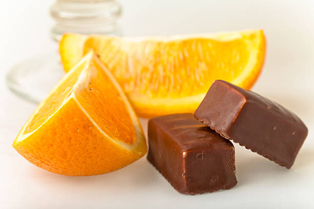 Two chocolates with orange slice close-up on white background stock photo