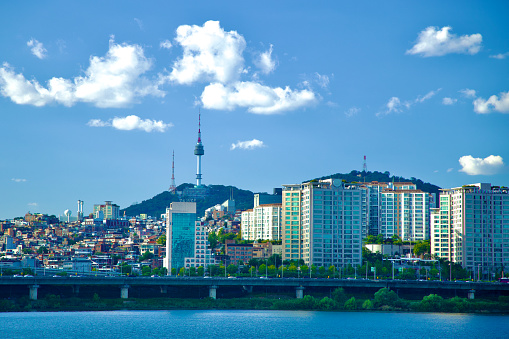 Seoul, South Korea - October 1, 2023: A picturesque scene of Itaewon neighborhood perched on a low hill along the banks of the Han River, framed by a blue sky dotted with a few clouds.