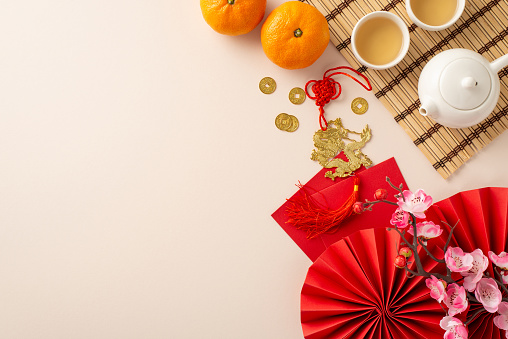 Transport yourself into heart of Chinese New Year: top view fans, Feng Shui artifacts, teapot set, green teaâ harmonious family tradition. Tangerines, sakura, pastel backdrop create canvas for your ad