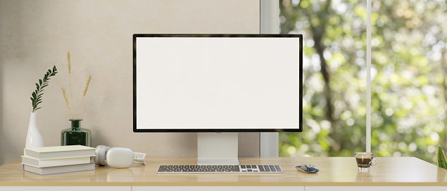 Modern minimal home workspace with a computer desk against the white wall and window, a computer white-screen mockup and accessories on a wooden table. close-up image. 3d render, 3d illustration