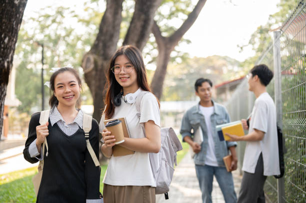 istock Two charming Asian female students with their backpack are standing on a footpath on their campus. 1856290916