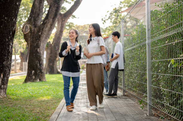 istock Two Asian female students best friends are enjoying talking while walking, going to school together. 1856290917