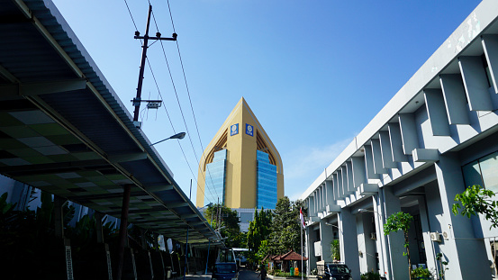 Surabaya, Indonesia - July 13, 2023: ASEEC Tower Airlangga University, a blue and gold tall building seen from below with clear sky. Bottom view, long distance shot