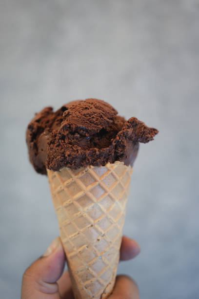 istock A hand holding of chocolate ice cream in a waffle cone 1856357020