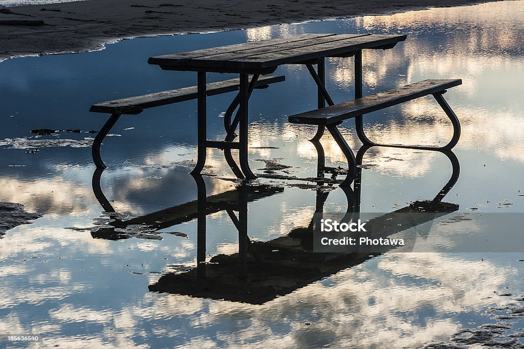 Picnic Table in Water with Reflected Sky A picnic table in the water in Presqu'ile Provincial Park, Ontario, Canada. Beach Stock Photo