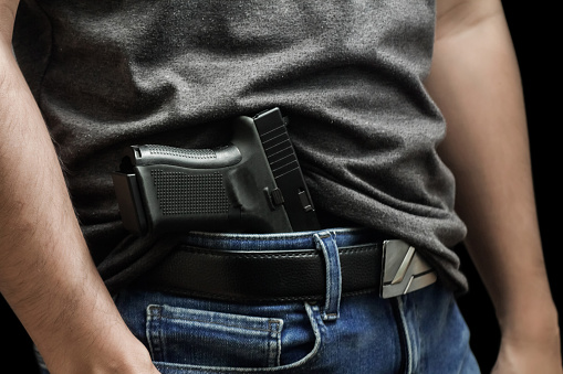 Man drawing a conceal carry pistol from a holster isolated on black background