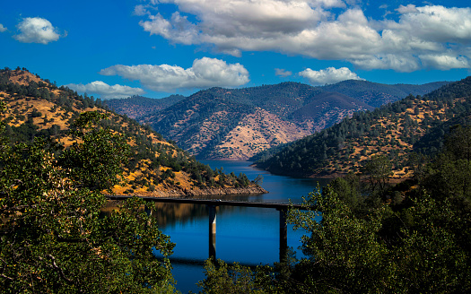 Water in lake Don Pedro and surrounding mountains with trees and bridge