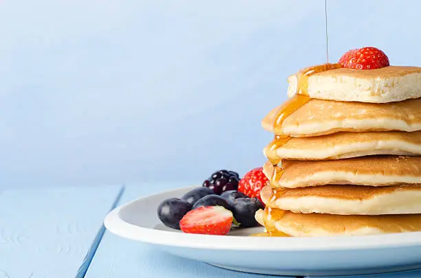 Photo of Stacked Pancakes and Fruit with Maple Syrup