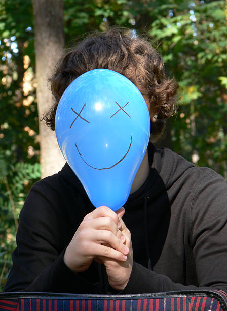istock Boy hiding behind balloon with smile 185643072