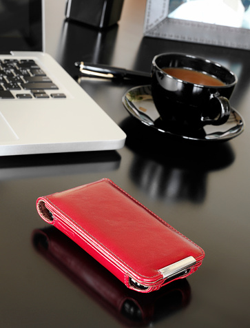Leather mobile phone cover on an office table with laptop and coffee