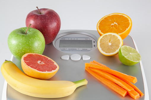 Fresh fruits on top of a weight scale symbolizing dieting