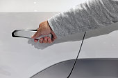 A man's hand is holding a new style car door handle.