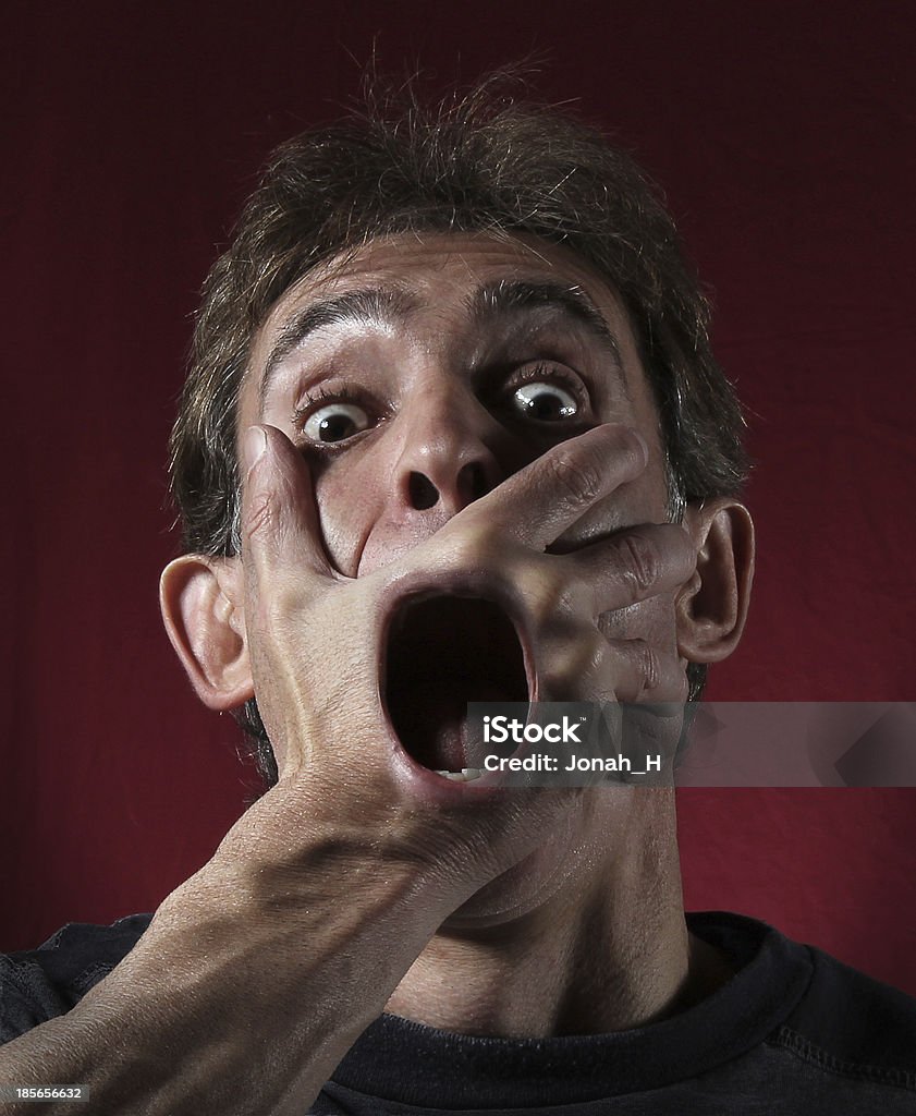 Macabre screaming face. A macabre composite image of a man screaming through a hand clenching his face. Fear Stock Photo