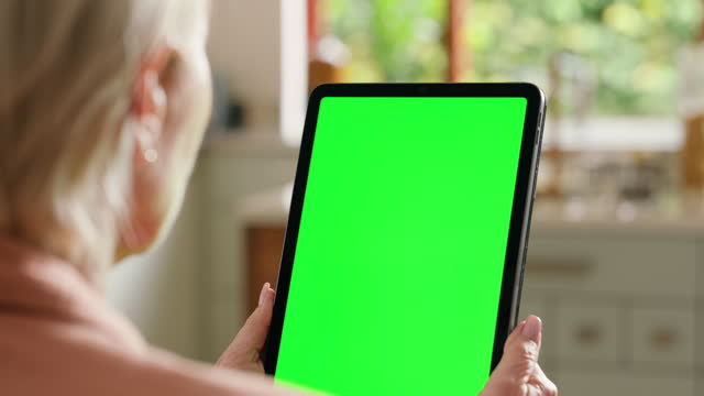 Hands of woman, tablet and green screen in home, online search or communication. Digital tech, closeup and chroma key mockup, networking or reading email on social media app, space and notification