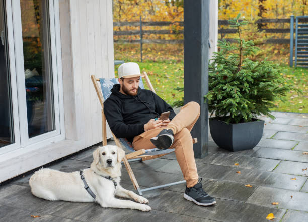 istock Young man sitting with dog on terrace 1856607414