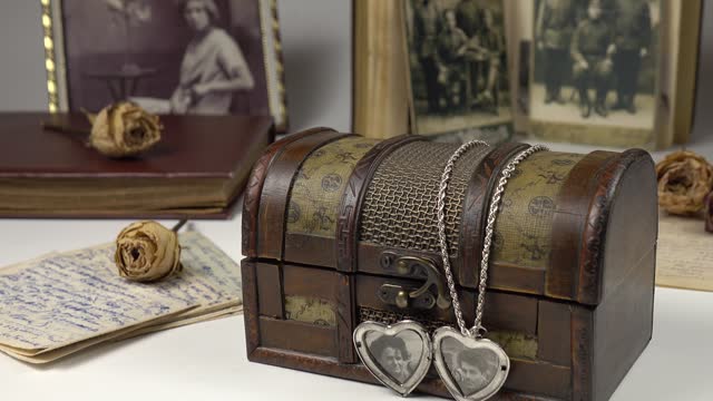 Old photographs and silver pendant in the shape of a heart with photographs are on a white table, memory, nostalgia.