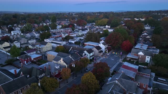 Small town America during autumn sunrise. Aerial view of main street with houses and homes and colorful fall foliage.
