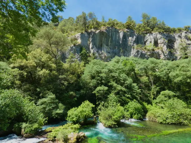 Photo of a magnificent provencal landscape with the beautiful Sorgue river and lush nature all around. This photo was taken at Fontaine de Vaucluse in Provence.